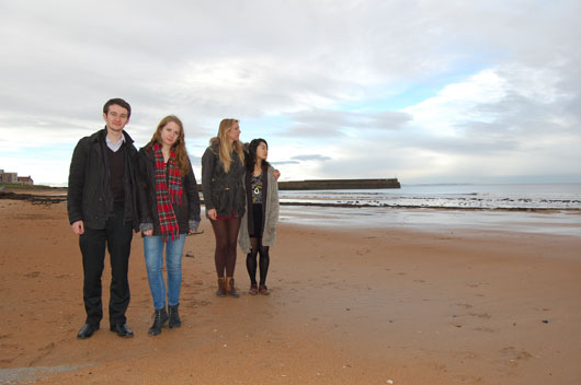 Four people standing on the beach