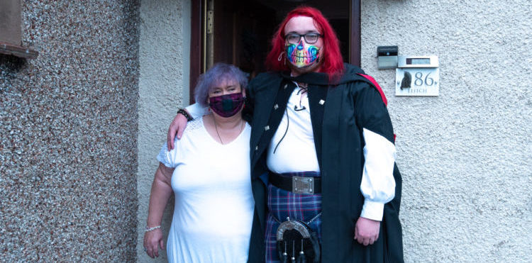 Two people stand in doorway wearing masks