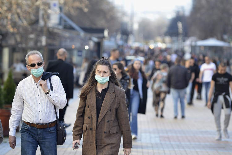 Man and woman walking in the the city center wearing protective masks