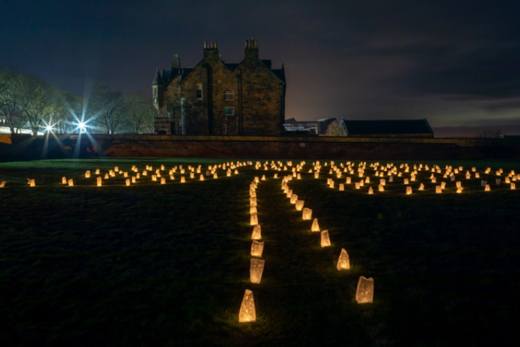 Nighttime, candles and lit on the grass and set out to form a path