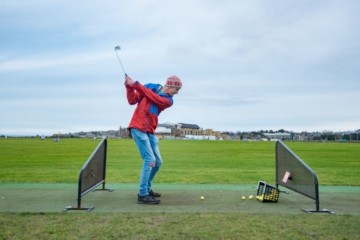 Student at a golf driving range, mid swing.