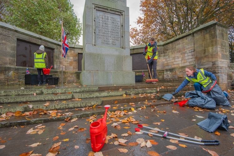 Three students cleaning up the St Andrews War Memorial
