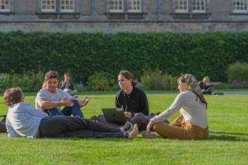 Four students sitting on a lawn