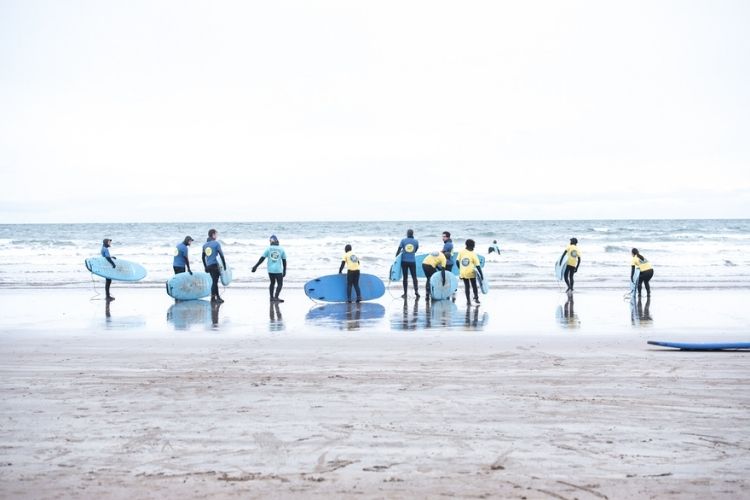 Group of students on the beach with surfboards