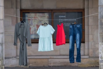 A clothes line is strung up between pillars in St Salvator's Quad, and hanging from it are four outfits including a pair of jeans and a dress.