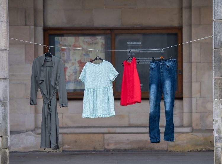 A clothes line is strung up between pillars in St Salvator's Quad, and hanging from it are four outfits including a pair of jeans and a dress.