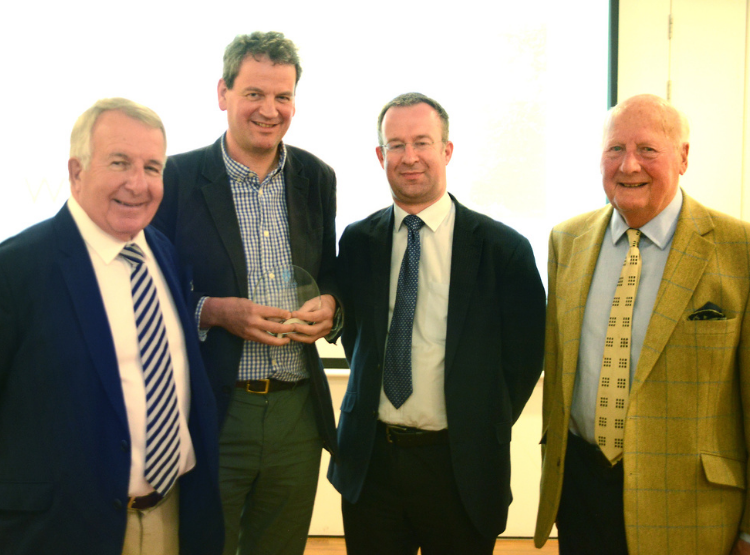 Two members of St Andrews Preservation Trust presenting a glass award to two male members of University staff. 