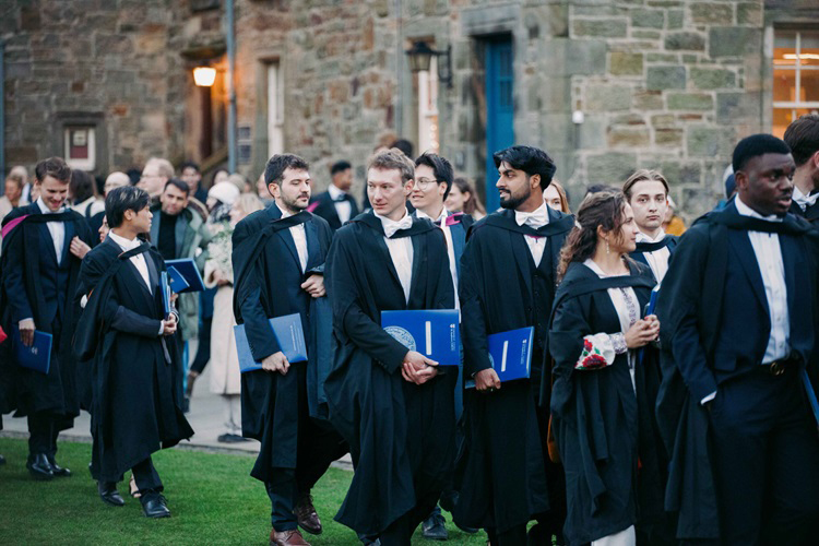 Students in academic dress group outside an old building