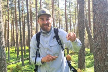 man holding an egg in a forest