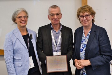 three people standing together one holding an award