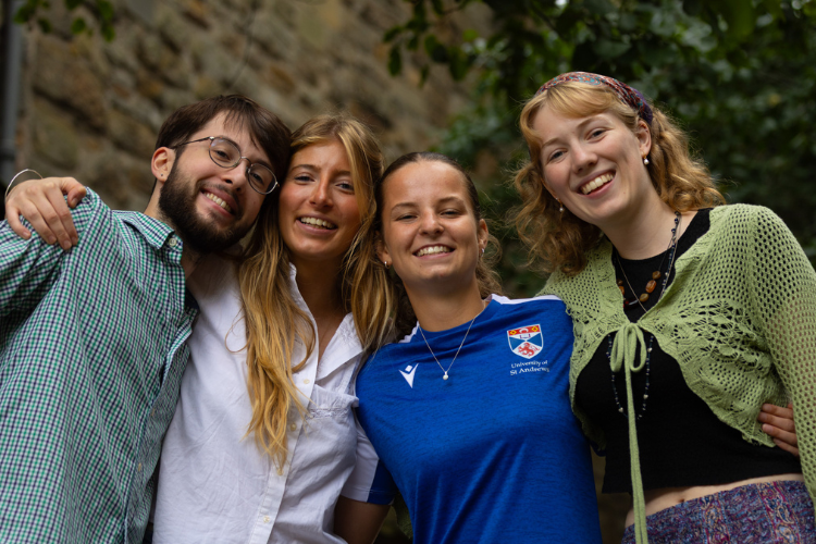 Four smiling students with their arms round one another